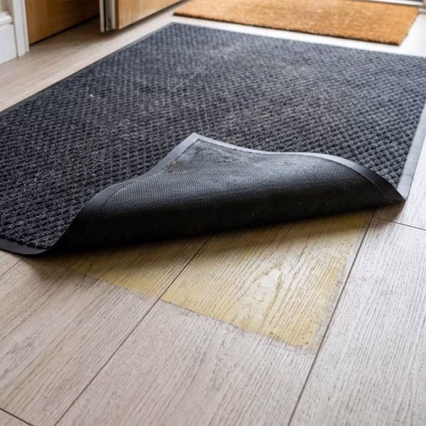 LVT Vinyl Floor Discolouration beneath rubber backed mat rolled back by corner
